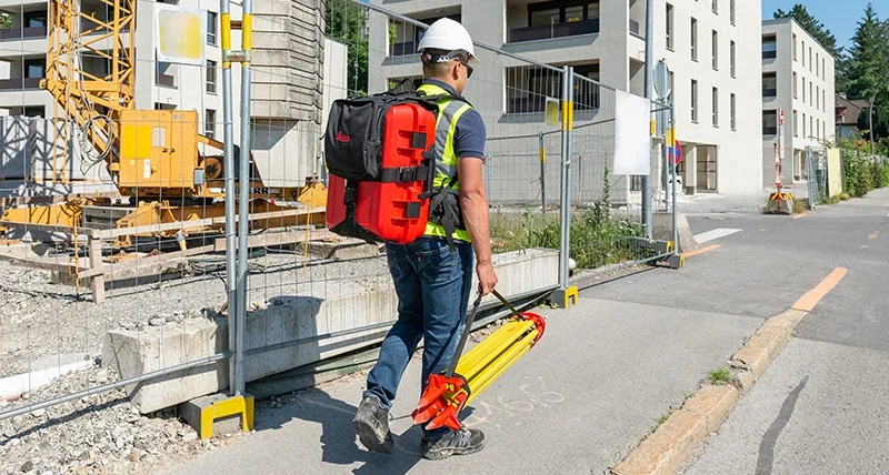 Técnico con escáner móvil en mochila midiendo una calle